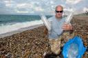 Steve Trewhella on Chesil Beach with just some of the hundreds of plastic cups that have washed up