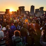 The sun rises between the stones and over crowds at Stonehenge  in 2019