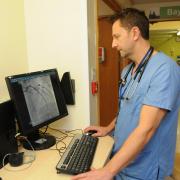 Consultant Cardiologist Dr Tim Wells looks at a coronary angiogram on screen. The dark area on the screen is the contrast that is used to outline the artery and identify if there are any blockages