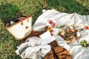 A picnic blanket and items laid out on the grass. Picture from Canva
