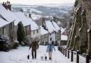 Dog walkers on a snowy Gold Hill in Shaftesbury - Picture from Andrew Matthews/PA Wire