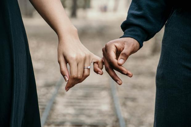 Salisbury Journal: A couple linking fingers while she wears an engagement ring. Credit: Canva