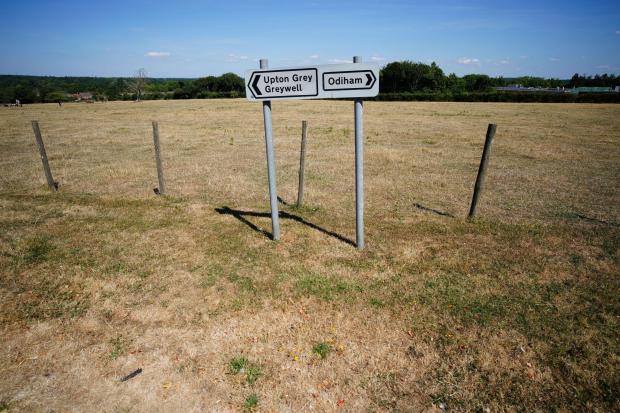 Parched grass surrounds signs in Hampshire, near the village of Odiham. Britain is braced for another heatwave that will last longer than July's record-breaking hot spell, with highs of up to 35C expected next week. Credit: PA Wire/PA Images