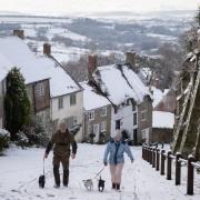 Dog walkers on a snowy Gold Hill in Shaftesbury - Picture from Andrew Matthews/PA Wire