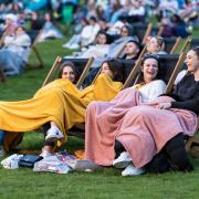 Four girls sitting with blankets at an outdoor cinema. Credit: Adventure Cinema