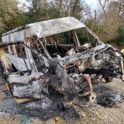 A stolen school minibus was dumped in a New Forest car park and set on fire.
