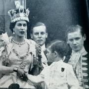 A young Prince Charles (now King Charles III) holds the hand of his mother Queen Elizabeth II at her Coronation