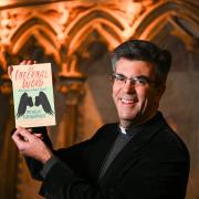The Dean of Salisbury, The Very Revd Nicholas Papadopulos with a copy of his book, The Infernal Word